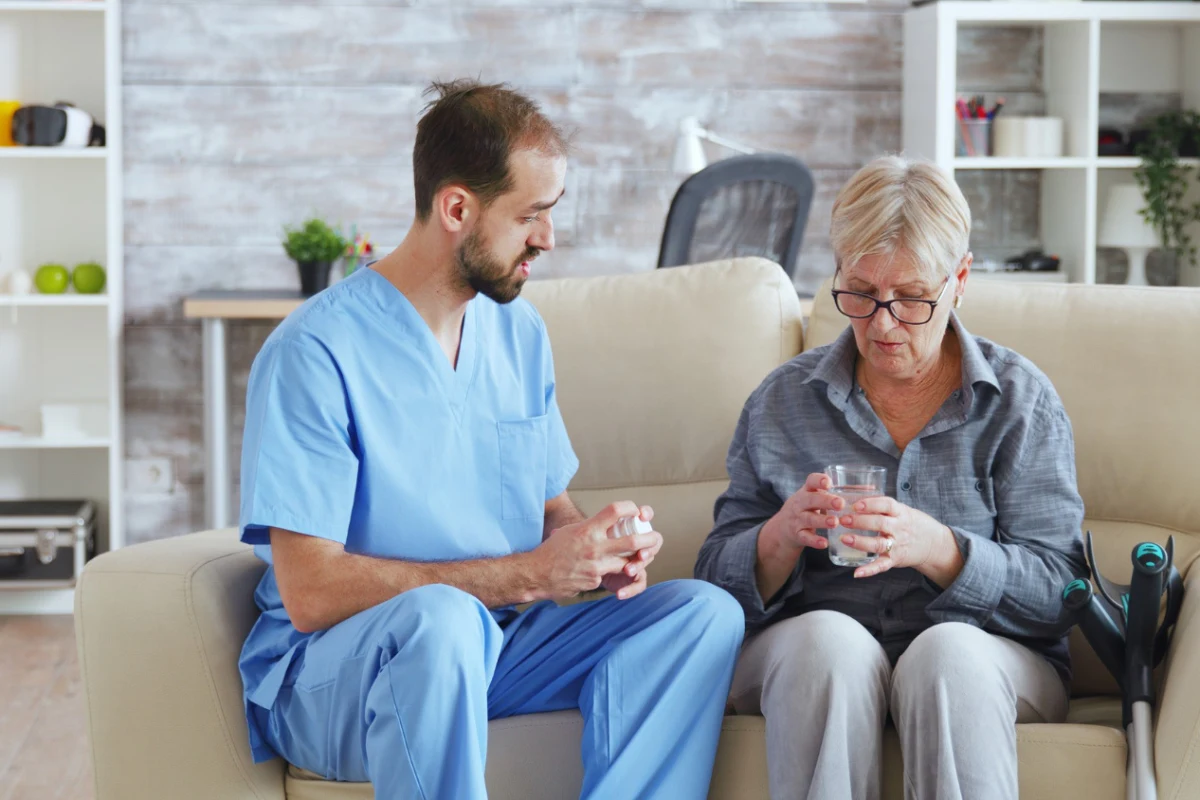 infirmier qui donne un medoc à une femme agée